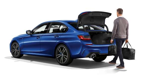 BMW 3 Series Sedan, automatic tailgate operation 플러그인 하이브리드 G20 Three-quarter rear shot of standing BMW 3 Series Sedan with driver automatically opening the tailgate with his foot 플러그인 하이브리드 G20.