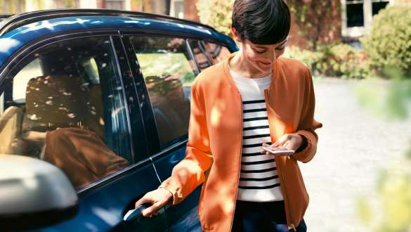 Woman looking at smartphone Woman getting out of BMW looking at smartphone