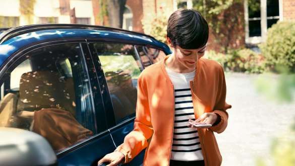 Woman looking at smartphone BMW 5 Series Sedan G30 Woman getting out of BMW looking at smartphone BMW 5 Series Sedan G30