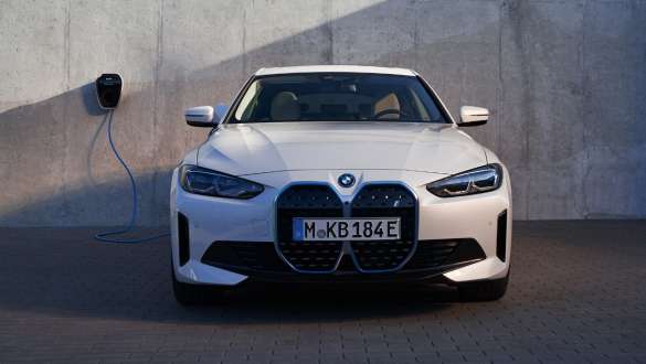 BMW 월박스가 있는 BMW i4 eDrive40 G26 2021 프론트 뷰 BMW 월박스 충전소가 있는 가정집 벽면 앞 BMW i4 eDrive40 G26 2021 미네랄 화이트 프론트 뷰