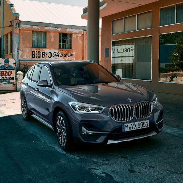 BMW X1 SUV F48, three-quarter front view. BMW X1 SUV F48, three-quarter front view standing in front of urban scenery.