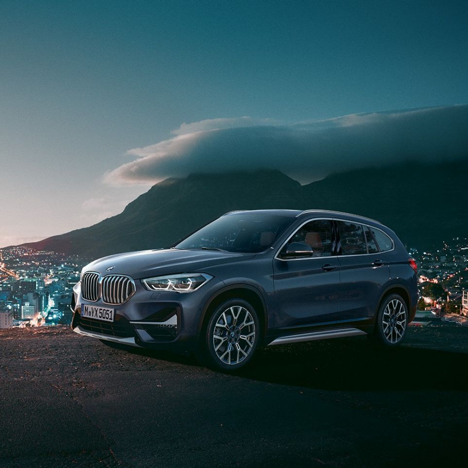 BMW X1 SUV F48, three-quarter side view. BMW X1 SUV F48, three-quarter side view standing in front of urban scenery.