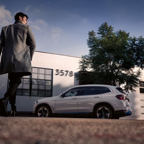 건물 앞에서 남성과 함께 자리한 BMW iX3 G08의 측면 모습 건물 앞에서 남성과 함께 자리한 BMW iX3 G08 2020 미네랄 화이트 메탈릭의 측면 모습