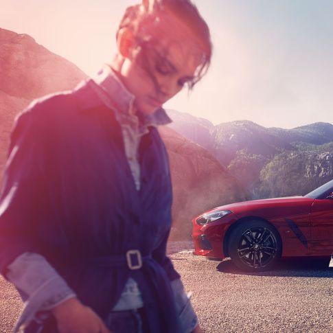 산악 경관 앞의 BMW Z4 로드스터의 앞모습 산악 경관 앞의 BMW Z4 로드스터와 여성과 남성