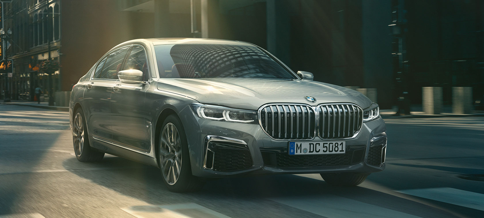 Grey BMW 7 Series Sedan driving, three-quarter front view Grey BMW 7 Series Sedan drives through the urban setting in the three-quarter front view