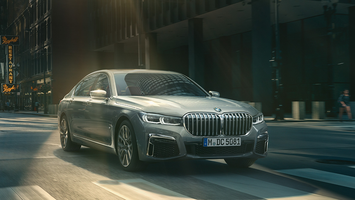 Driving Assistant Professional: three-quarter front view of BMW 7 Series Sedan driving in front of urban setting 플러그인 하이브리드 G11 Driving Assistant Professional: three-quarter front view of BMW 7 Series Sedan driving in front of urban setting 플러그인 하이브리드 G11