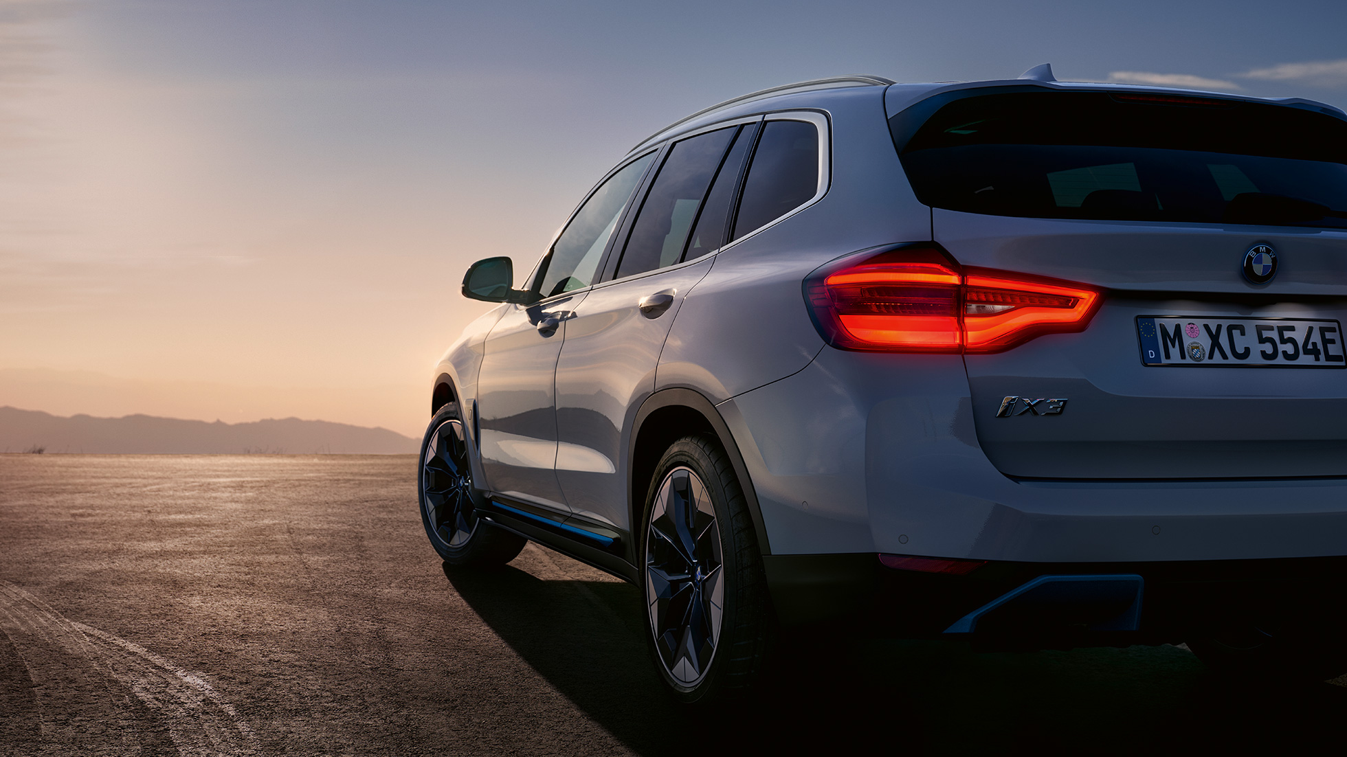 도로 주행 중인 BMW iX3 G08의 후면을 3/4각도(반측면)에서 바라본 모습 도로 주행 중인 BMW iX3 G08 2020 미네랄 화이트 메탈릭의 후면을 3/4각도(반측면)에서 바라본 모습