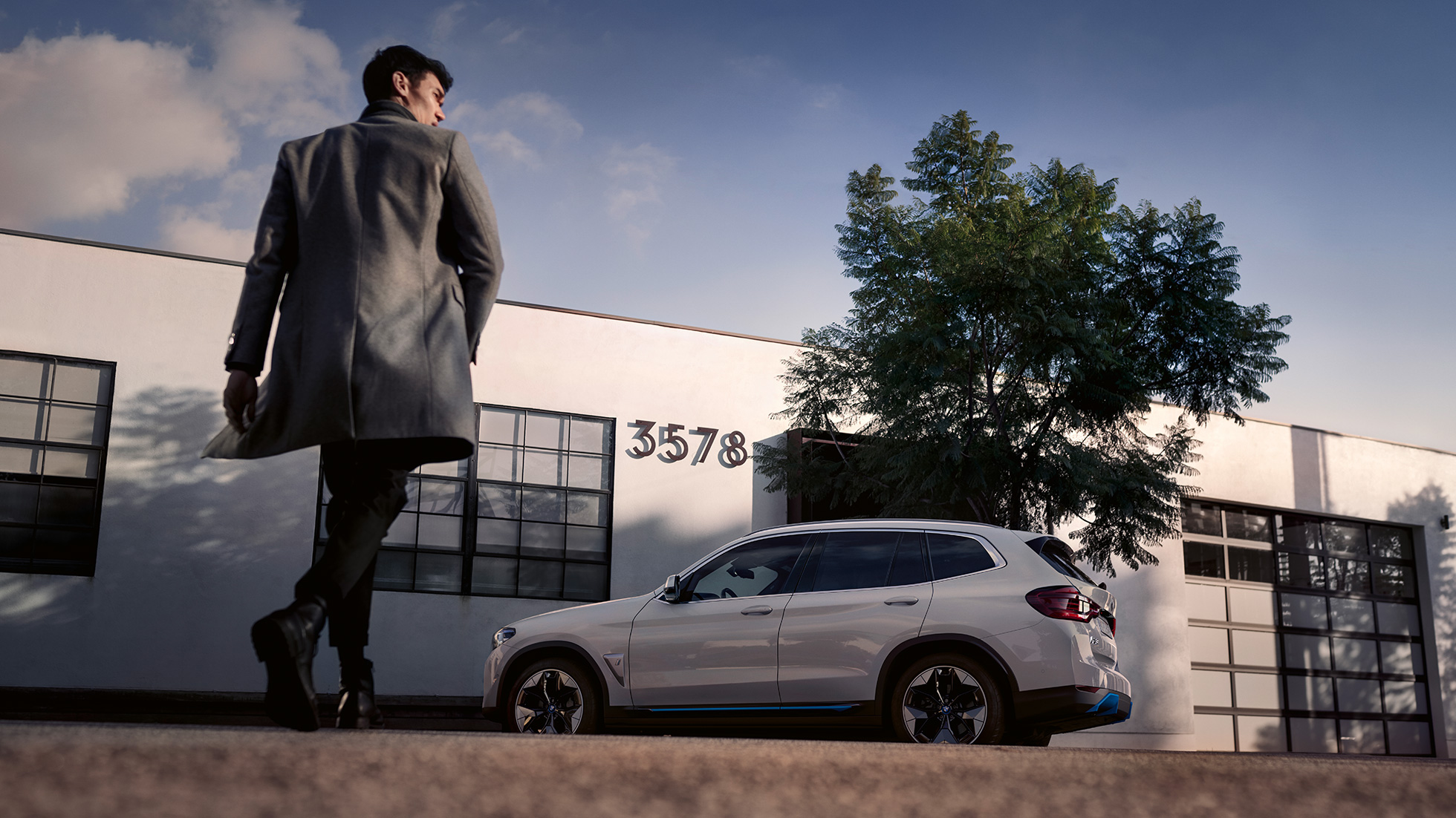 건물 앞에서 남성과 함께 자리한 BMW iX3 G08의 측면 모습 건물 앞에서 남성과 함께 자리한 BMW iX3 G08 2020 미네랄 화이트 메탈릭의 측면 모습