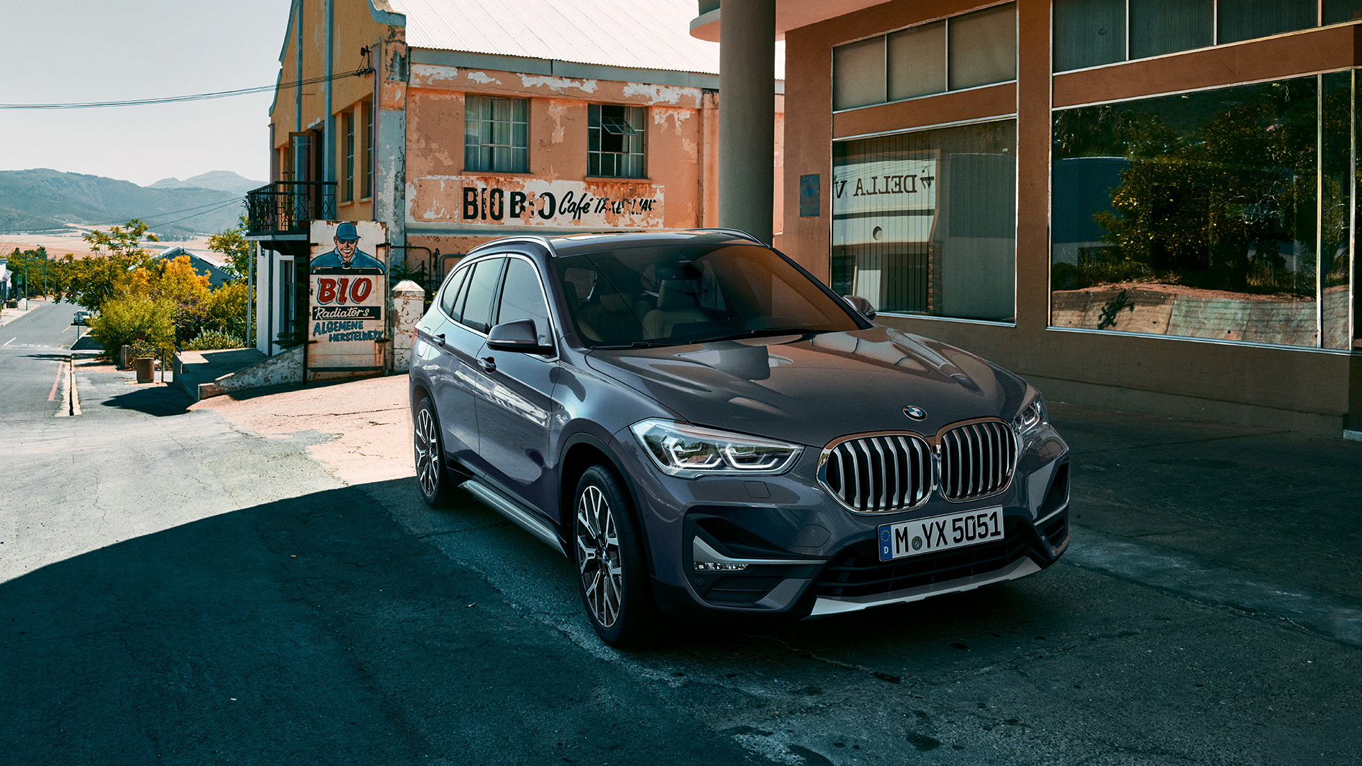 BMW X1 SUV F48, three-quarter front view. BMW X1 SUV F48, three-quarter front view standing in front of urban scenery.