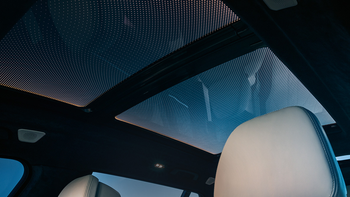 Ambient light SUV G07 View from the front row of seats up to the panorama glass roof framed by the orange ambient light SUV G07