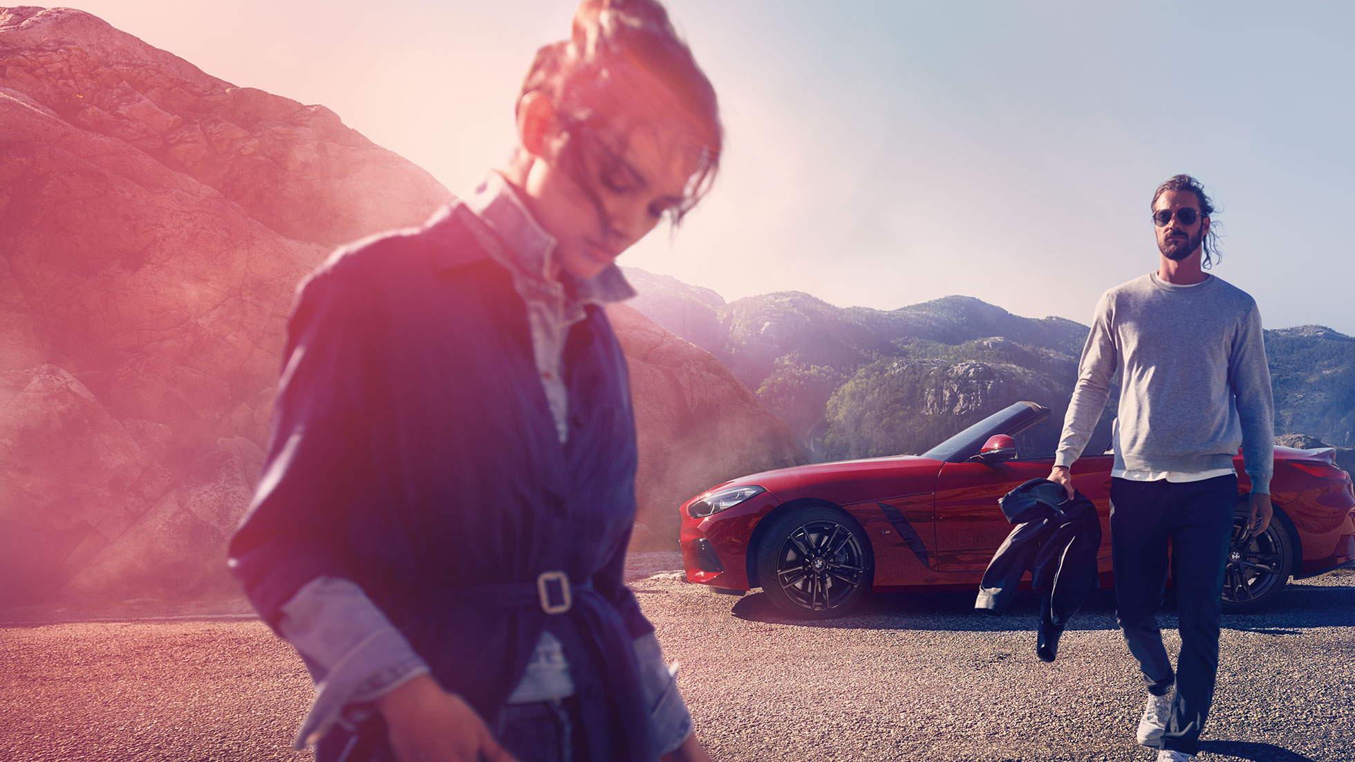 산악 경관 앞의 BMW Z4 로드스터의 앞모습 산악 경관 앞의 BMW Z4 로드스터와 여성과 남성